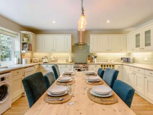 a kitchen with a long wooden table and blue chairs at 4 Bed in Burley NFL81 in Burley