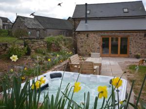 a bath tub in a garden with yellow flowers at 3 Bed in Tiverton 49356 in Uplowman