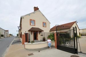 a woman standing next to a gate in front of a house at Le Cep de Bouzy gite 6 personnes au cœur du vignoble champenois in Bouzy