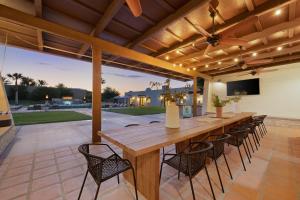 an outdoor patio with a wooden table and chairs at Starlight Estate by AvantStay 26 People Architectual Mansion w Pool Tennis Court Game Room in Bermuda Dunes