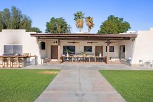 an outdoor patio with a table and chairs at Starlight Estate by AvantStay 26 People Architectual Mansion w Pool Tennis Court Game Room in Bermuda Dunes