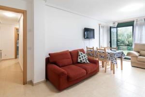 sala de estar con sofá rojo y mesa en Apartamento Llanes Paraiso 206, en Posada de Llanes