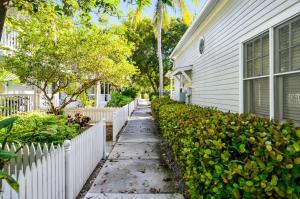 a sidewalk next to a house with a white fence at Lavender Jungle by AvantStay Great Location w Patio Shared Pool Week Long Stays Only in Key West