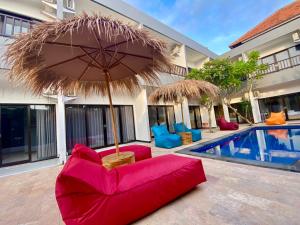 a red couch and an umbrella next to a pool at Hotel Summer Of Surf in Ungasan