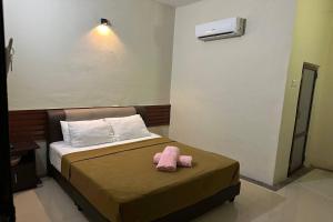 a pink stuffed animal sitting on top of a bed at Bull & Bear Airport Hotel Langkawi in Kuah