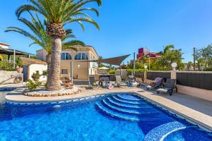 - une piscine avec un palmier à côté d'une maison dans l'établissement Villa Campanilla - Plusholidays, à Calp