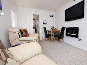uma sala de estar com um sofá e cadeiras e uma televisão em 1 Bed in Lyme Regis 62615 em Axminster