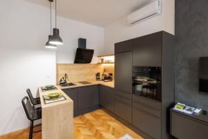 a kitchen with black cabinets and a table and a counter at New Green Studio Apartment near Tvrđa in Osijek