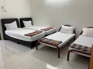 um quarto com três camas e um banco em Go Holiday Taiping Homestay em Simpang
