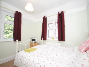 a bedroom with a bed and two windows at 4 Bed in Studland DC046 in Studland