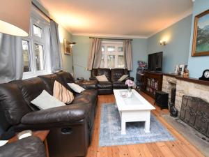 a living room with a leather couch and a table at 4 Bed in Studland DC046 in Studland