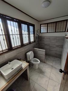 a bathroom with a toilet and a sink and windows at Baan Mai Muang Nan in Nan