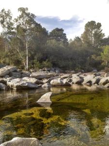a river with rocks and trees in the background at Casa de adobe Cuesta blanca in Cordoba