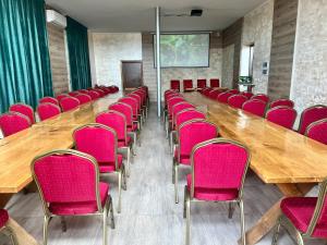 una sala de conferencias con sillas rosas y una gran mesa de madera. en Czar Podlasia agroturystyka, en Osłowo