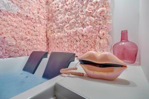 einen Tisch mit einer rosa Skulptur und einer Glasflasche in der Unterkunft La Vie en Rose / Jacuzzi in Montgeron