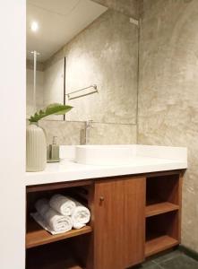 La salle de bains est pourvue d'un lavabo et d'un comptoir avec des serviettes. dans l'établissement Waterfront Suites Phuket by Centara NEW, à Phuket