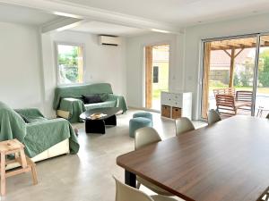 un salon avec des meubles verts et une table en bois dans l'établissement Maison avec piscine et jardin privatifs - un séjour au calme, à Biscarrosse