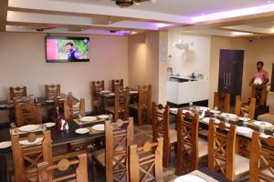 Un comedor con mesas y sillas y un televisor. en Hotel Sweet Villa Puri, en Puri