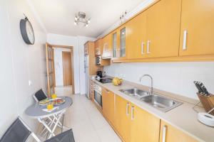 a kitchen with wooden cabinets and a sink and a table at Apartamento Bellavista Puerto 3 in Cala Ratjada +27 photos