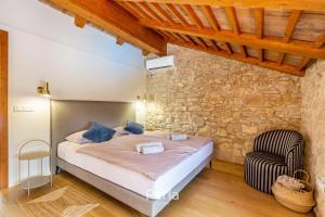 ein Schlafzimmer mit einem Bett und einem Stuhl in der Unterkunft Charming stone Villa CX with large 50m2 heated pool in Brtonigla