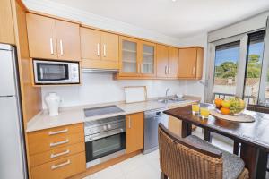 a kitchen with wooden cabinets and a table at Apartamento Bellavista Puerto 4B in Cala Ratjada