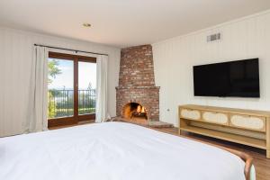 a bedroom with a bed and a fireplace at Dume Point by AvantStay Tennis Pool in Malibu in Malibu