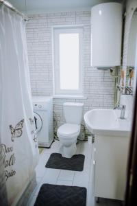 a white bathroom with a toilet and a sink at Світанок у горах in Verkhniy Yasenov