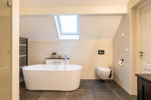 een badkamer met een wit bad en een toilet bij Villa Zuiderduin in Zoutelande