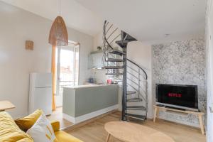 ein Wohnzimmer mit einer Wendeltreppe und eine Küche in der Unterkunft Duplex spacieux et design proche la Part-Dieu in Lyon