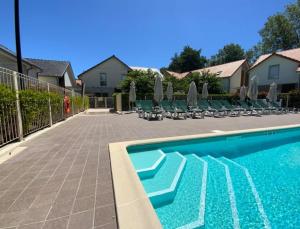 - une piscine avec des chaises longues et des parasols dans l'établissement Maison 6 personnes avec terrasse, piscines et sauna, à Pornichet