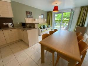 eine Küche und ein Wohnzimmer mit einem Holztisch und Stühlen in der Unterkunft Maison 6 personnes avec terrasse, piscines et sauna in Pornichet
