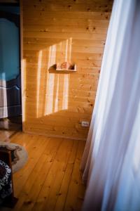 een kamer met een houten muur, een raam en een gordijn bij Світанок у горах in Verkhniy Yasenov