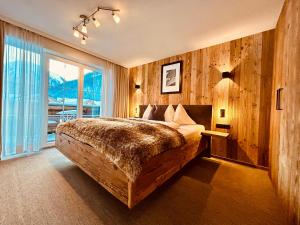 - une chambre avec un grand lit et une grande fenêtre dans l'établissement Sonn-Alm Chalet-Apartments, à Bichlbach