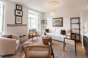 FLH Downtown Central Arammish Apartment في لشبونة: غرفة معيشة مع أريكة بيضاء وكراسي