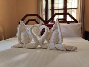 2 serviettes en forme de cygne assises sur un lit dans l'établissement Hakuna Matata Villa, à Paje