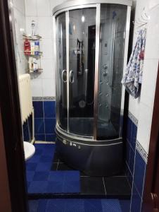 a bathroom with a shower with a blue tiled floor at Гостевой дом Энесай in Bishkek
