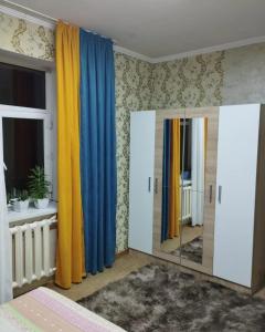 a bedroom with blue and yellow curtains and a mirror at Гостевой дом Энесай in Bishkek