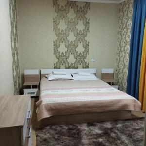 - une chambre avec un grand lit et un mur dans l'établissement Гостевой дом Энесай, à Bishkek