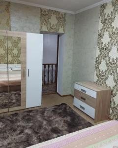 a bedroom with a bed and a dresser and a mirror at Гостевой дом Энесай in Bishkek