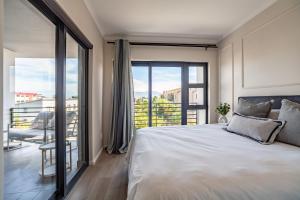 una camera da letto con un letto grande e un balcone di Chic Modern 2 bedroom beachfront with views, 6 Blue Tides a Bloubergstrand