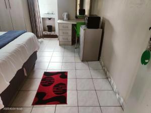 GREEN TREE في Mtubatuba: غرفة نوم مع سرير وسجادة حمراء على الأرض