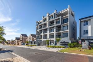 un condominio bianco in una strada con case di Chic Modern 2 bedroom beachfront with views, 6 Blue Tides a Bloubergstrand