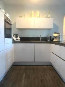 cocina con armarios blancos y suelo de madera en Luxuriöse Loft Wohnung in Paderborn en Paderborn