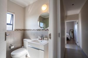 un bagno con un water, un lavandino e uno specchio di Chic Modern 2 bedroom beachfront with views, 6 Blue Tides a Bloubergstrand Altre 45 foto