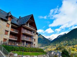 a building on a hill with mountains in the background at Apartamentos Sallent de Gállego 3000 in Sallent de Gállego