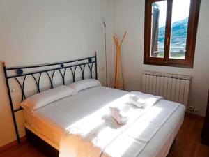 1 dormitorio con 1 cama con sábanas blancas y ventana en Apartamentos Sallent de Gállego 3000, en Sallent de Gállego
