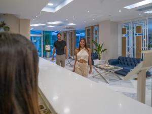 a man and woman walking down a staircase in a lobby at Secret Paradise Hotel & Spa in Nea Kallikrateia