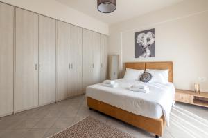 een slaapkamer met een bed met witte lakens en kasten bij Zephyrus Cityscape Condo,By IdealStay Experience in Heraklion
