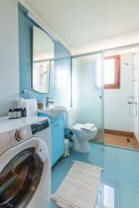 een blauwe badkamer met een wasmachine bij Zephyrus Cityscape Condo,By IdealStay Experience in Heraklion