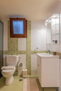 een badkamer met een toilet, een wastafel en een raam bij Zephyrus Cityscape Condo,By IdealStay Experience in Heraklion
